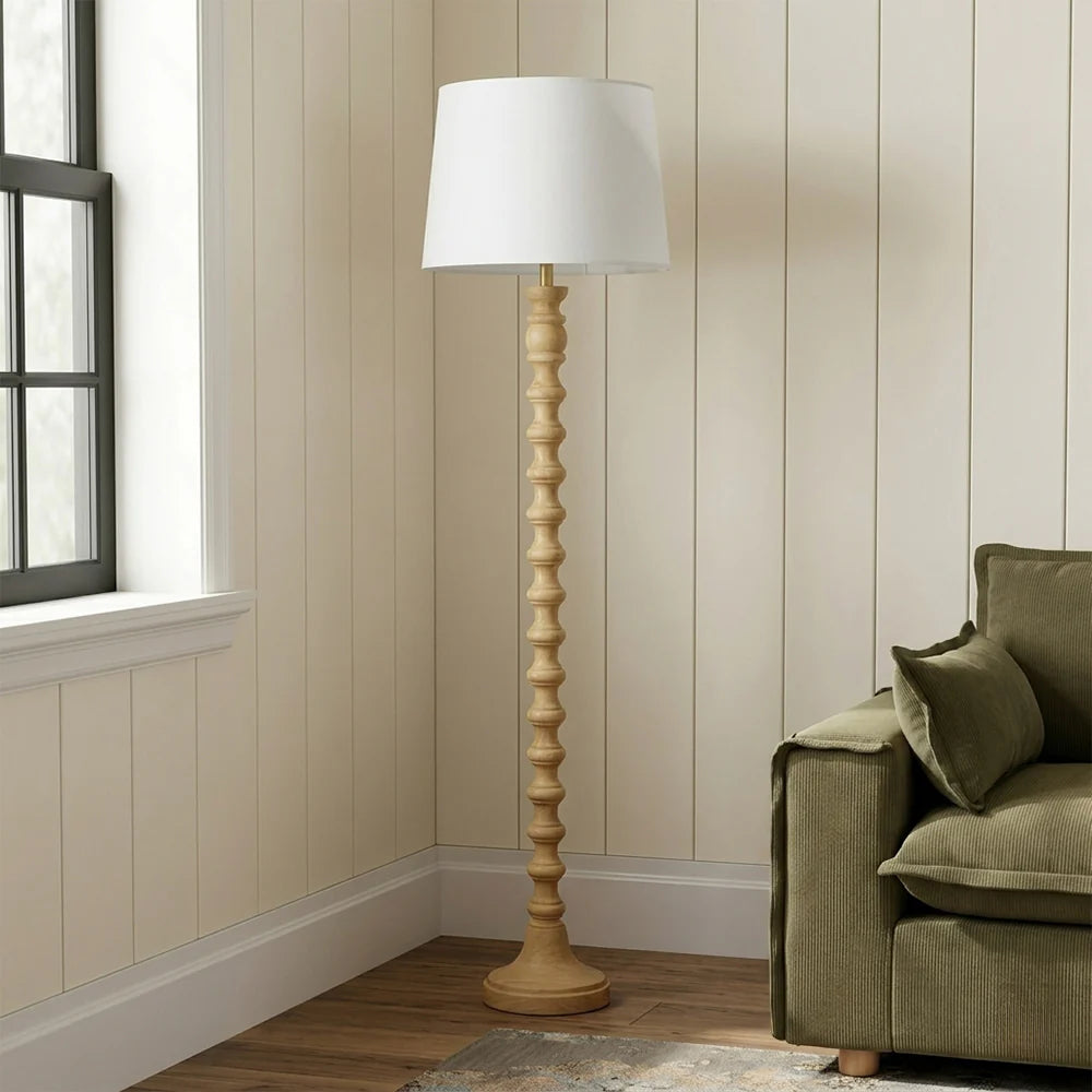 Wooden floor lamp with white shade in a living room setting.