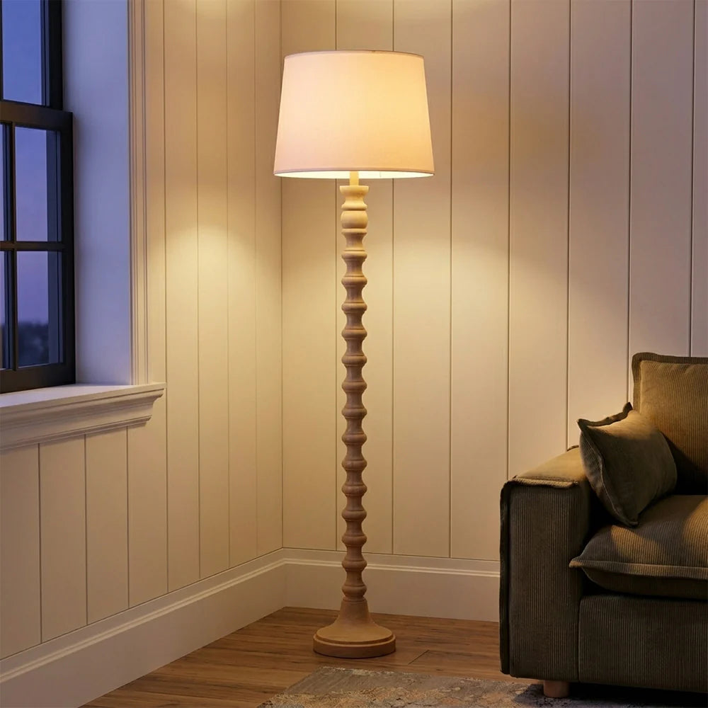 Wooden floor lamp in a room with a couch and window