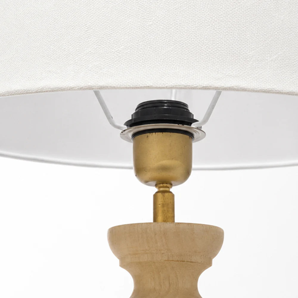 Close-up of a lamp with wooden base, brass fitting, and white shade.