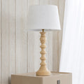 Table lamp with wooden base and white shade on a light wooden surface.