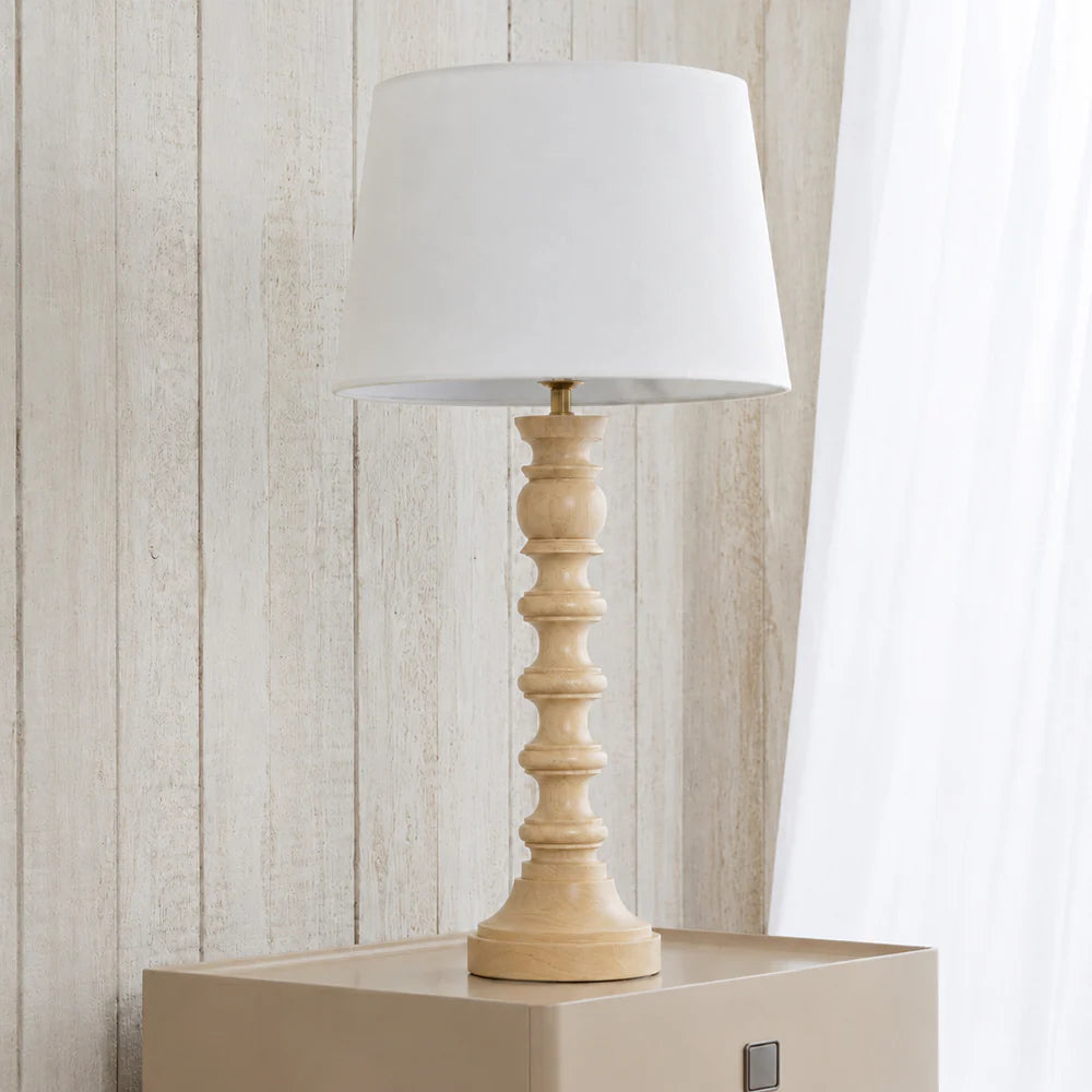 Table lamp with wooden base and white shade on a light wooden surface.