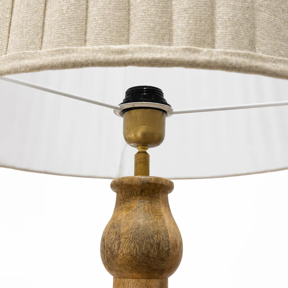 Close-up of a lamp with a wooden base and beige lampshade on a white background